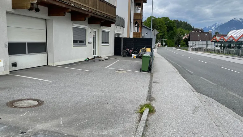 Außenansicht des Gebäudes mit Garagentor und gepflastertem Parkplatz an der Straße.