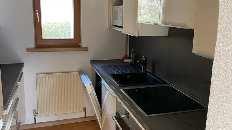 Moderne Küche mit weißen Hochglanzfronten, Induktionskochfeld, Backofen und integriertem Geschirrspüler.