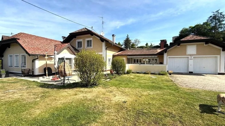Großzügiger Gartenbereich mit Rasenfläche und Blick auf das Haus mit Garagen.