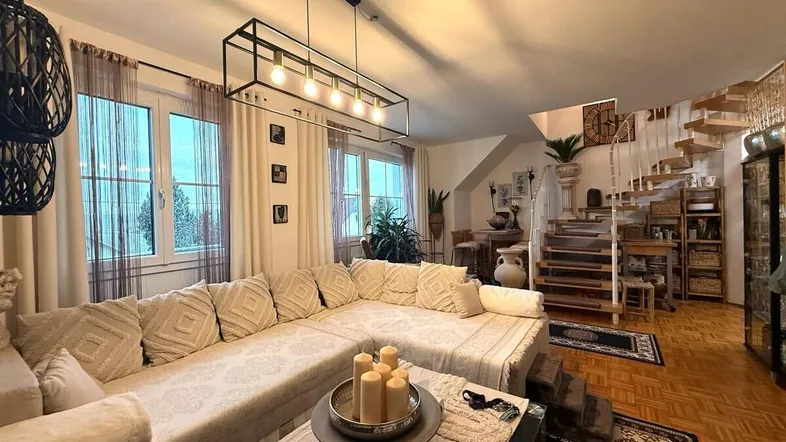 Geräumiges Wohnzimmer mit großer Eckcouch, Holzparkett und Wendeltreppe zum oberen Stockwerk.