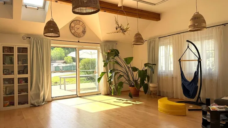 Helles Wohnzimmer mit Holzboden, hohen Decken, sichtbaren Balken und Zugang zur Terrasse.
