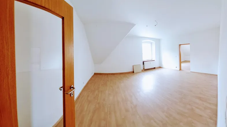Helles Dachgeschosszimmer mit Laminatboden, schrägen Wänden und einem Fenster, das viel Tageslicht hereinlässt.