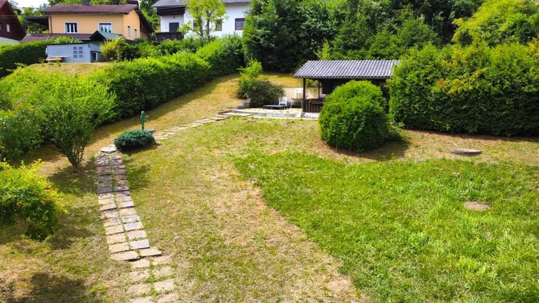 Gepflegter Gartenbereich mit Steinpfad, umgeben von Hecken und Bäumen, ideal zum Entspannen.