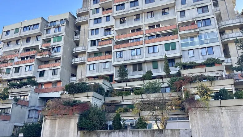 Mehrstöckiges Wohngebäude mit vielen Balkonen und begrünten Terrassen in moderner Architektur.