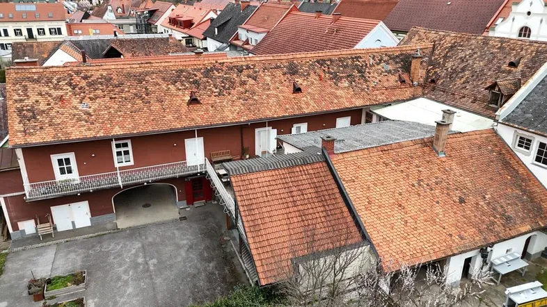 Luftaufnahme des Anwesens mit roten Ziegeldächern und Innenhof, umgeben von weiteren Gebäuden.