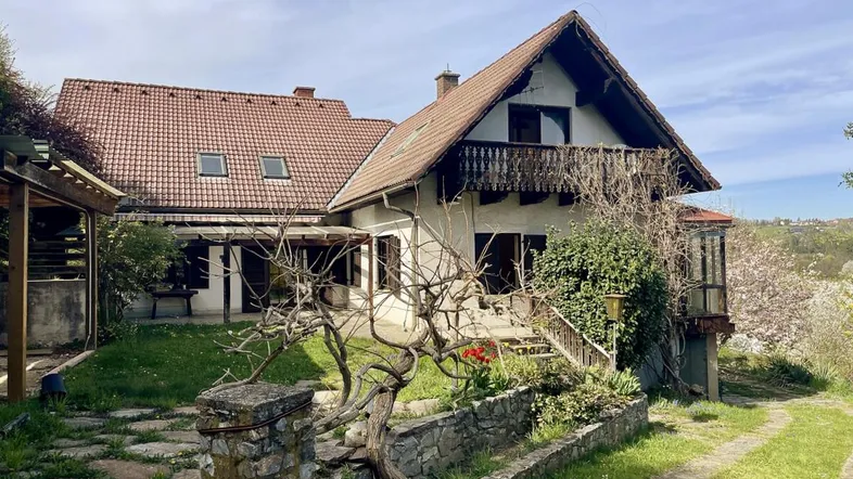 Traditionelles Haus mit Satteldach, Balkon und gepflegtem Vorgarten in ländlicher Umgebung.