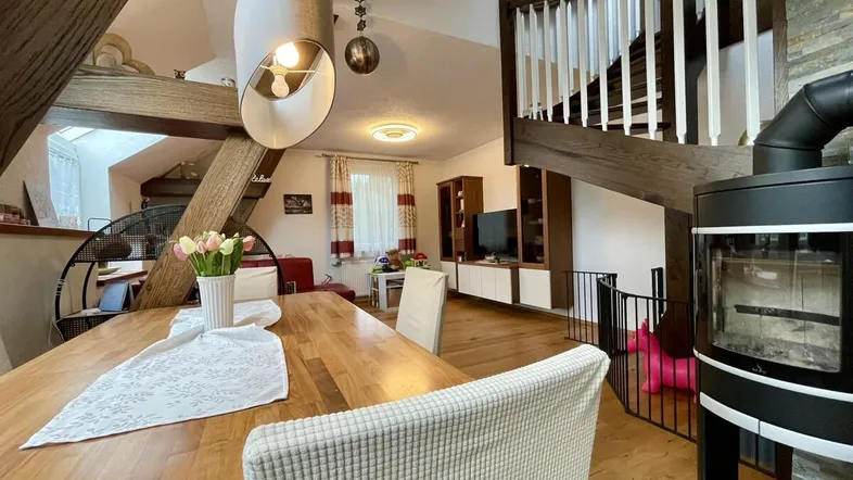 Geräumiger Wohn- und Essbereich mit Holzboden, Kaminofen und offener Holztreppe.