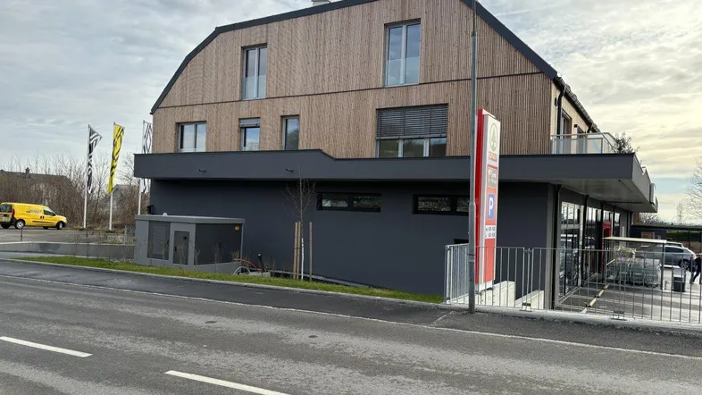 Modernes Gebäude mit Holzfassade und Flachdach, integriert in eine städtische Umgebung.