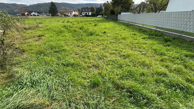 Weitläufiges grünes Grundstück mit Blick auf die umliegende Landschaft und entfernte Häuser.