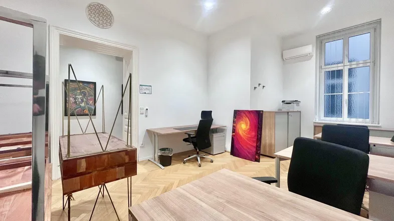 Helles Büro mit mehreren Arbeitsplätzen, Parkettboden und großen Fenstern, ideal für eine moderne Arbeitsumgebung.