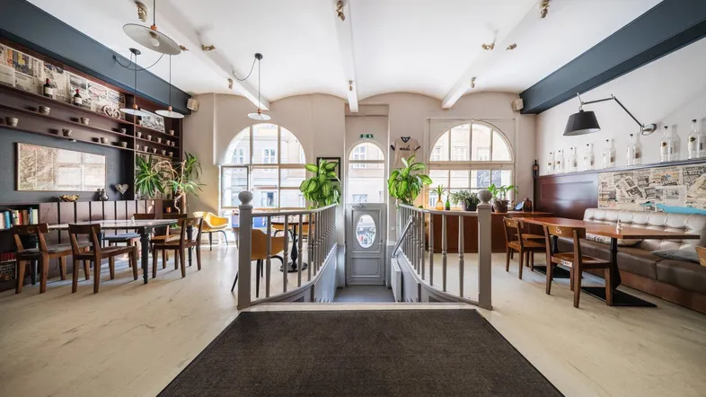Geräumiger Restaurantbereich mit verschiedenen Sitzgelegenheiten, hohen Decken und großen Rundbogenfenstern.