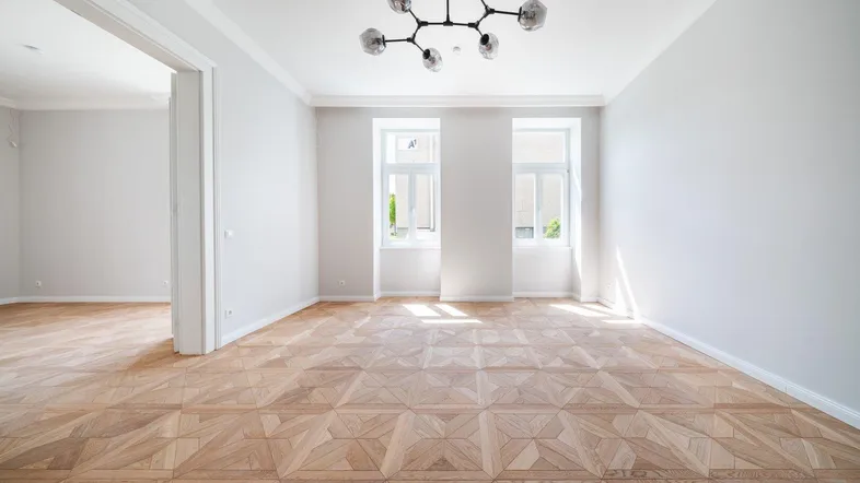 Helles, geräumiges Zimmer mit elegantem Parkettboden und hohen Decken, ideal als Wohnbereich.