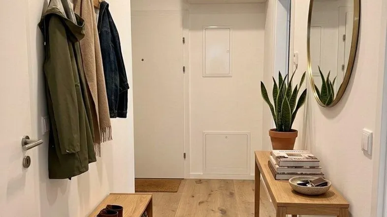 Heller Eingangsbereich mit Garderobe, Schuhbank und einem dekorativen Spiegel, der den Raum optisch vergrößert.
