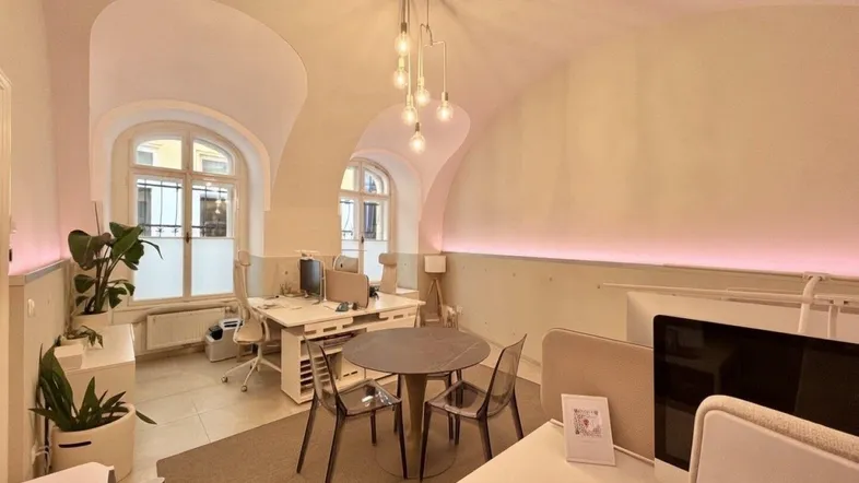 Modernes Büro mit gewölbter Decke, großen Fenstern und mehreren Arbeitsplätzen, hell beleuchtet.