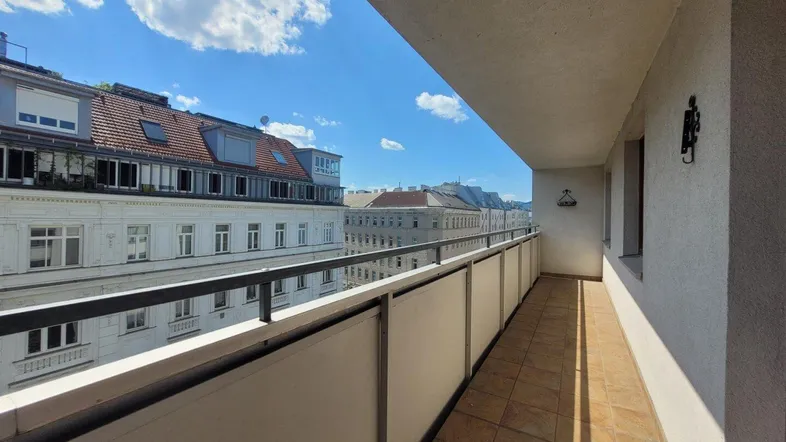 Langer Balkon mit Fliesenboden und Blick auf die umliegenden Gebäude der Stadt.