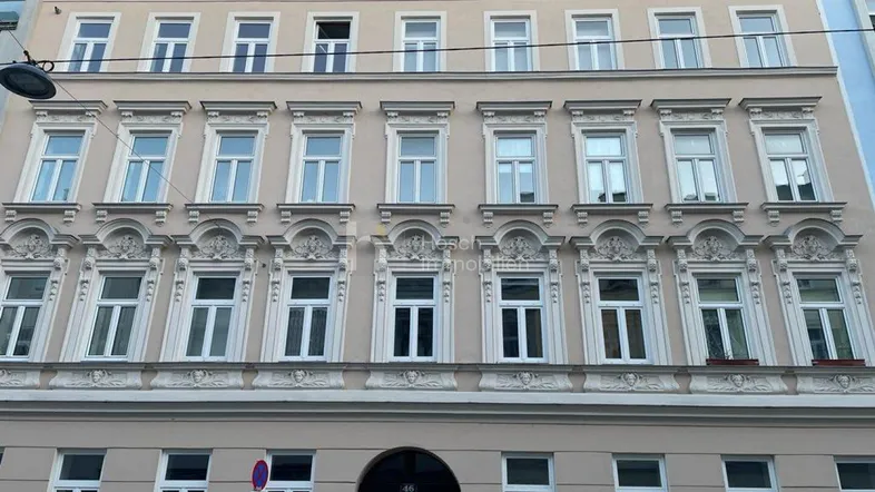 Detailansicht der historischen Fassade eines Mehrfamilienhauses mit reich verzierten Fenstern und Stuckelementen.