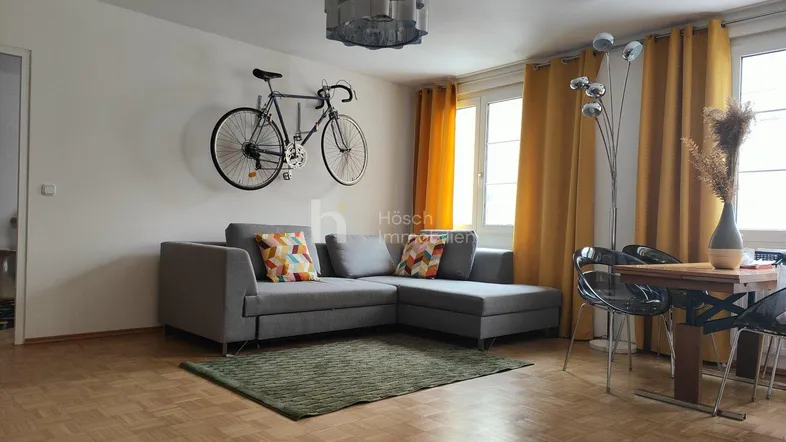 Helles Wohn- und Esszimmer mit Parkettboden, bequemer Sitzecke und einem Esstisch für gesellige Runden.