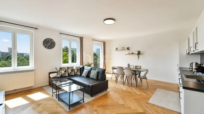 Helles Wohn- und Esszimmer mit offener Küche, Fischgrätparkett und Blick ins Grüne.