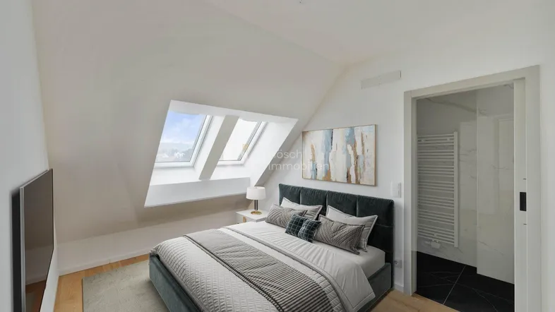 Helles Schlafzimmer mit Dachschrägen, gemütlichem Bett und Zugang zu einem modernen Badezimmer.
