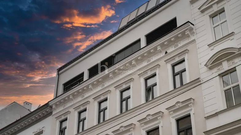 Historische Fassade eines Stadthauses mit modernen Dachaufbauten und einem dramatischen Himmel.