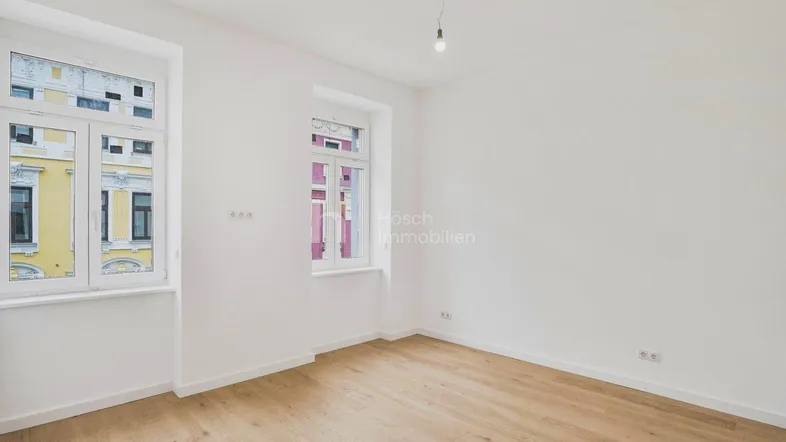 Helles, leeres Zimmer mit neuem Parkettboden und weißen Wänden, bereit für die Einrichtung.