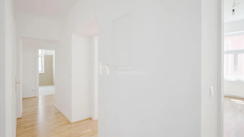 Heller Flur mit Parkettboden, der zu verschiedenen Zimmern führt und viel Tageslicht bietet.