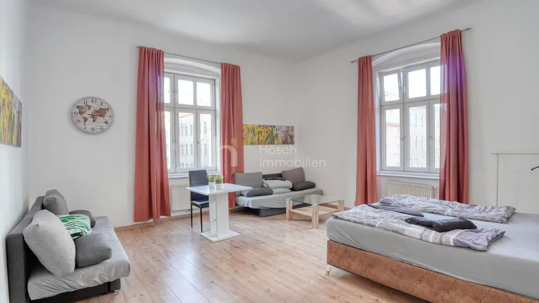 Helles Schlafzimmer mit Holzboden, großem Bett und Sitzgelegenheiten, ideal für ein Studio-Apartment.