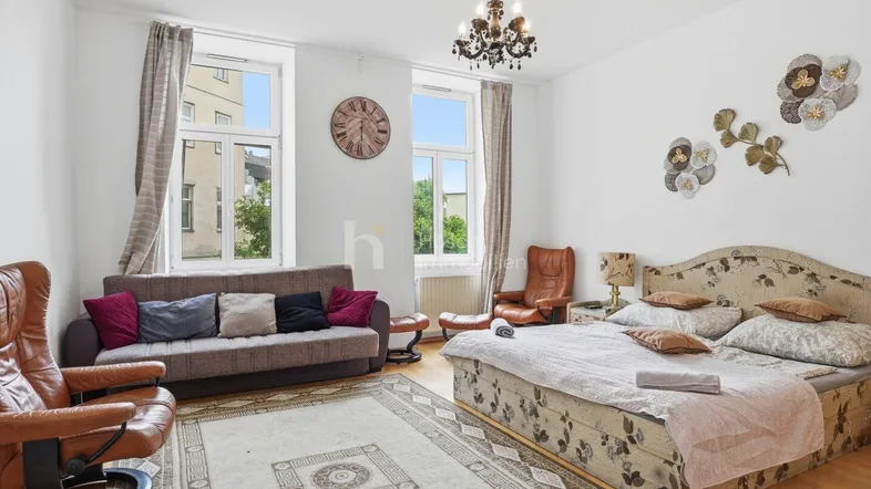 Geräumiges Schlafzimmer mit großem Bett, bequemen Sesseln und Blick auf die Stadt.