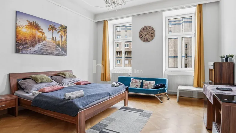 Helles Schlafzimmer mit Holzboden, bequemen Möbeln und Kronleuchter, ideal für entspannte Nächte.
