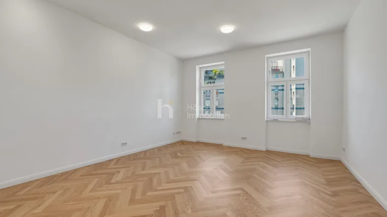 Helles Zimmer mit Fischgrätparkettboden und weißen Wänden, bereit zur individuellen Gestaltung.