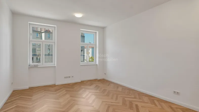 Helles Zimmer mit Fischgrätparkett und weißen Wänden, ideal als Wohn- oder Schlafzimmer nutzbar.
