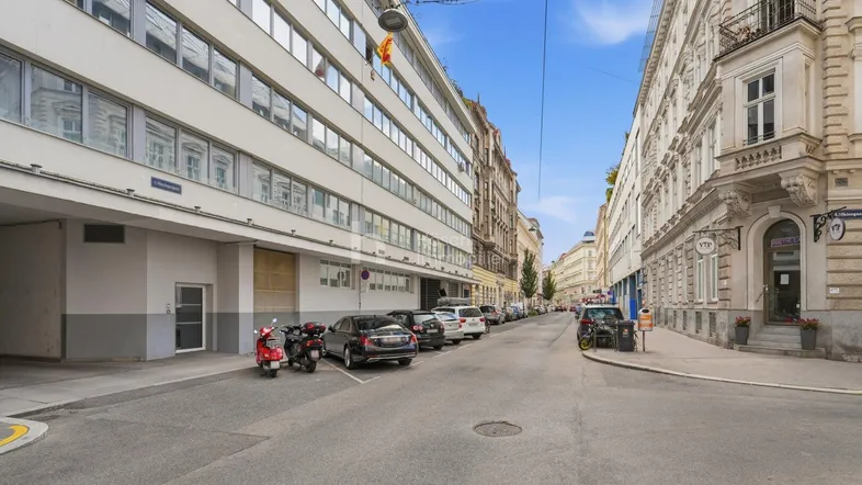 Blick auf die Straße mit einem modernen Gebäude auf der linken Seite und traditionellen Häusern auf der rechten Seite.
