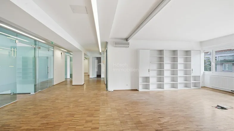 Großer, heller Raum mit Parkettboden und modernen Glasabtrennungen, vielseitig nutzbar.