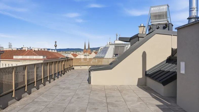 Geräumige Dachterrasse mit Fliesenboden und weitem Blick über die Stadt.