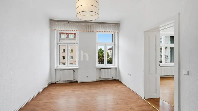 Helles Zimmer mit Laminatboden und Blick auf die umliegenden Gebäude, ideal als Wohn- oder Schlafzimmer.