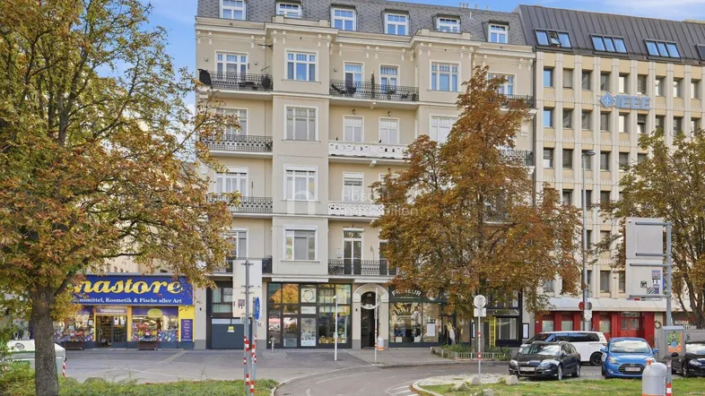 Elegantes Mehrfamilienhaus mit klassischer Fassade und Geschäften im Erdgeschoss in städtischer Umgebung.