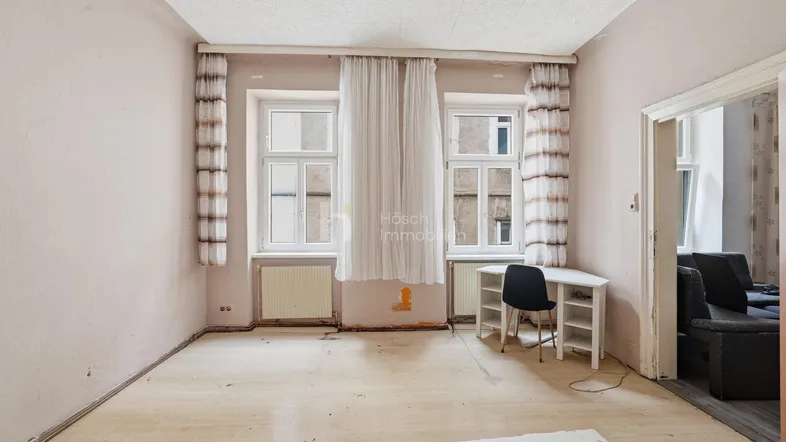 Helles Zimmer mit hellem Holzboden und zwei Fenstern, bereit für eine Renovierung.