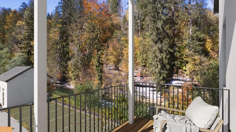 Gemütlicher Balkon mit Sitzgelegenheit und malerischem Blick auf den Fluss und herbstliche Bäume.