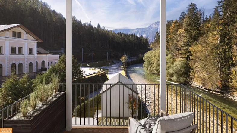 Geräumiger Balkon mit Blick auf einen Fluss, bewaldete Berge und ein historisches Gebäude.