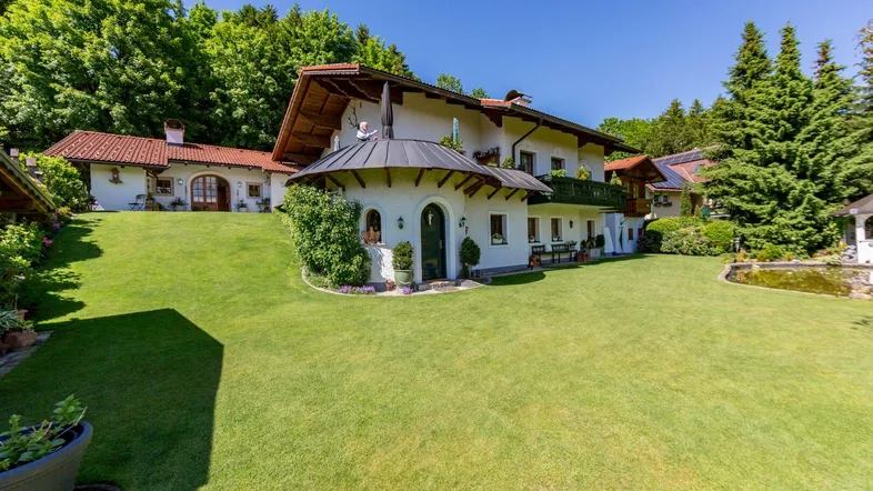 Großzügiger Gartenbereich mit gepflegtem Rasen und traditionellem Landhausstil-Gebäude unter blauem Himmel.