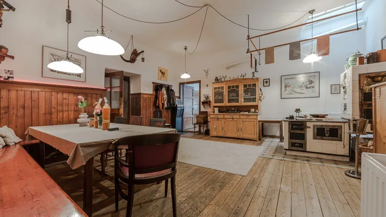 Rustikaler Wohn-Essbereich mit Holzboden, traditionellem Kachelofen und gemütlicher Sitzecke.