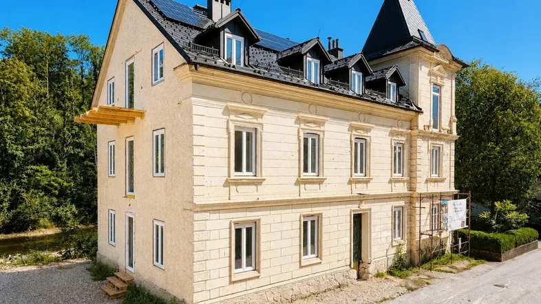 Elegantes Gebäude mit historischer Architektur, modernen Dachfenstern und Photovoltaikanlage.