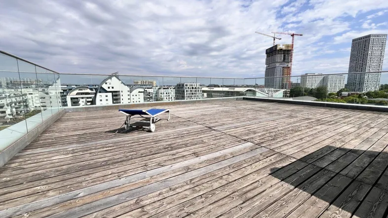 Geräumige Dachterrasse mit Holzboden und weitem Blick über die Stadt und umliegende Gebäude.