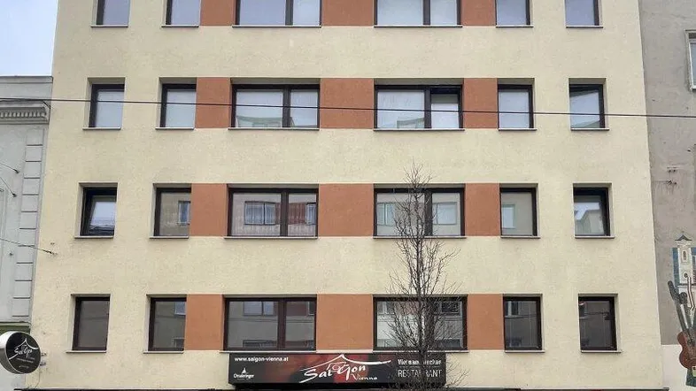 Vorderansicht eines mehrstöckigen Gebäudes mit Geschäftsflächen im Erdgeschoss und moderner Fassade.
