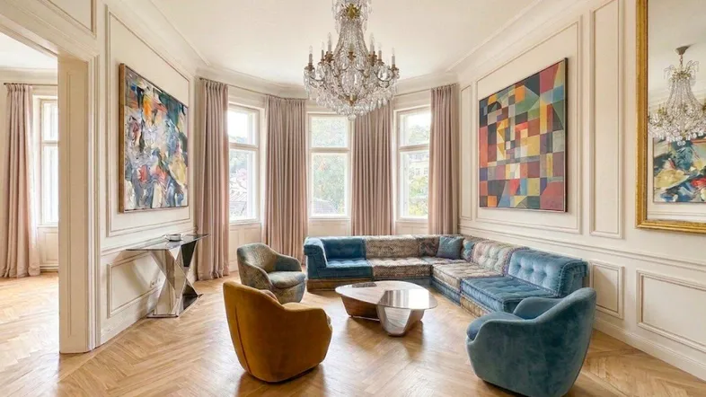 Elegantes Wohnzimmer mit Fischgrätparkett, hohen Decken, Kronleuchter und stilvollen Möbeln.