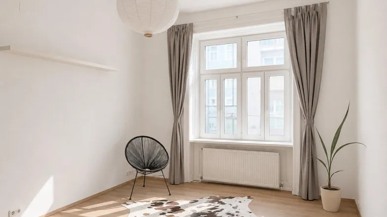 Helles Zimmer mit Parkettboden, großem Fenster und moderner Pendelleuchte.