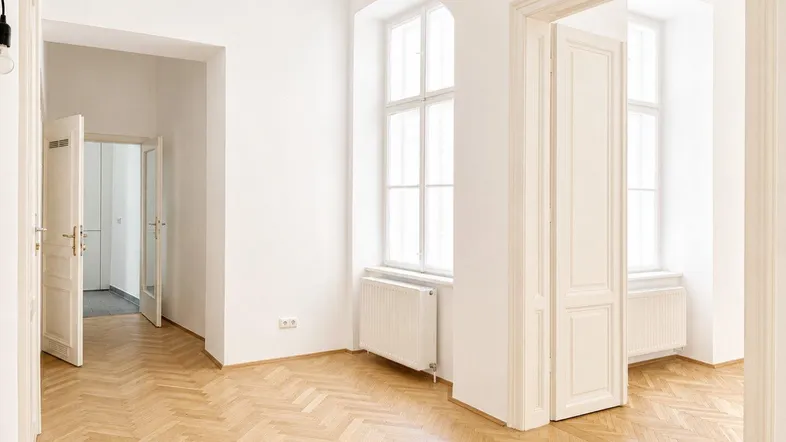 Heller Raum mit Fischgrätparkett, hohen Fenstern und weißen Wänden, bereit zur individuellen Gestaltung.