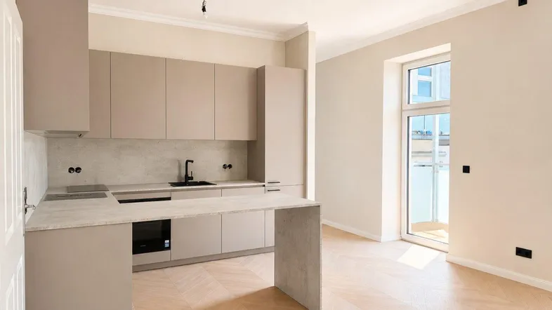 Moderne Einbauküche in hellem Beige mit Kochinsel und Fischgrätparkett in einem offenen Wohnbereich.