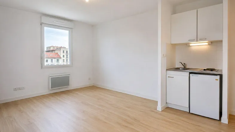 Helles Wohnzimmer mit integrierter Küchenzeile, Laminatboden und Fensterblick auf die Stadt.