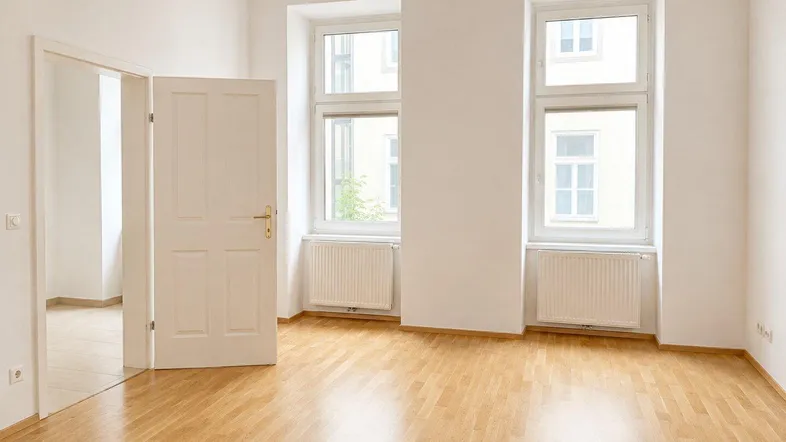 Helles Zimmer mit Parkettboden und zwei großen Fenstern, bereit zur individuellen Gestaltung.